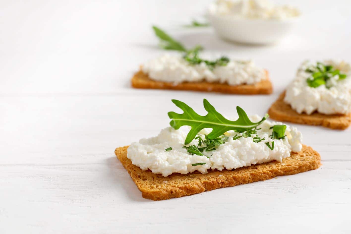 Cottage cheese on whole grain crackers with arugula